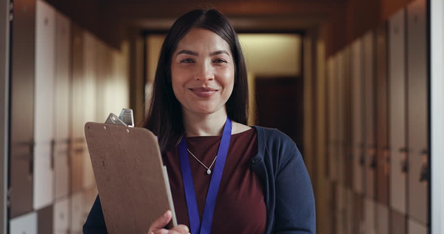 Education, teacher and clipboard with smile in school corridor for learning, knowledge and happiness inside. College, working and portrait of woman on campus at university for lecture and teaching Royalty-Free Stock Footage #1108169487
