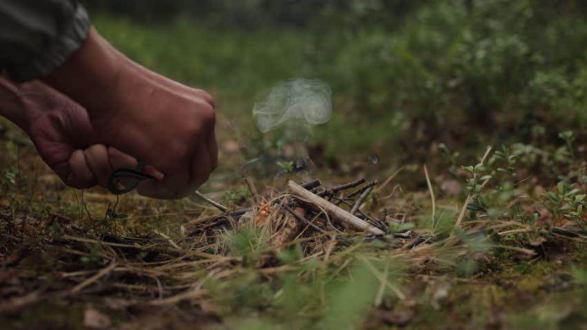 Man outdoors makeing fire by flint. Flamethrower. Survival in the wild