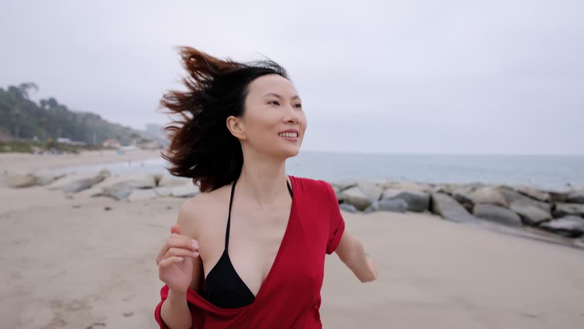 Attractive Asian woman running on the beach in Santa Monica California. Slow Motion.