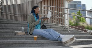 Young African American woman student or freelancer making video call using laptop computer sitting outdoor