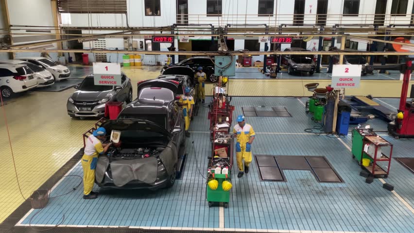 Yogyakarta, Indonesia - August 22, 2023: Several Honda car mechanics are carrying out routine maintenance services or repairing broken cars. The atmosphere in a large workshop full of work tools. 4k
