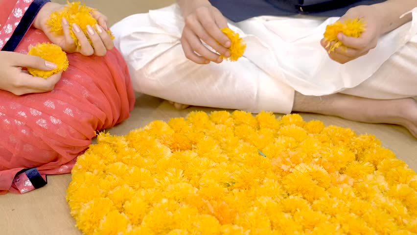 Indian couple making Rangoli using flowers