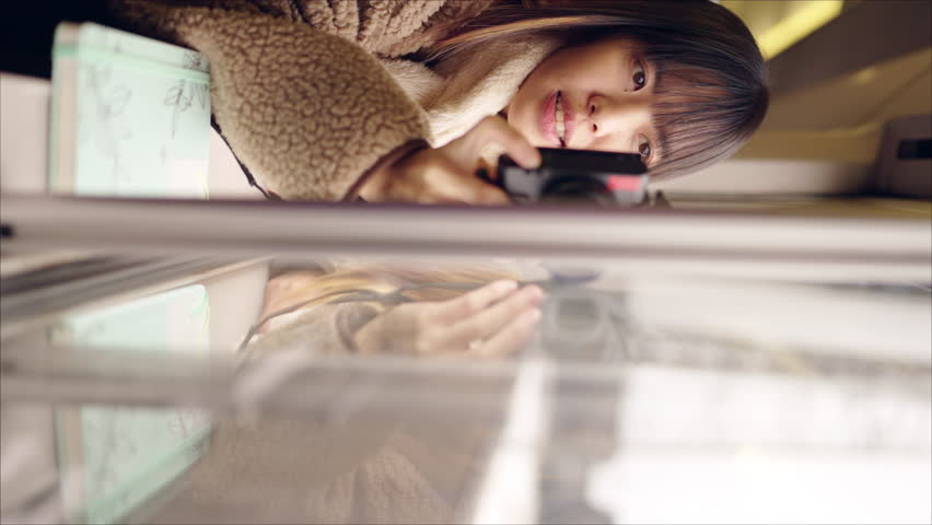 Young Asian woman using digital camera taking picture of beautiful view out of the window during travel on train at sunset. Attractive girl travel Japan on railroad transportation on winter vacation.