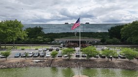 Patriotic Scene: American Flag Waving in Front of Corporate Office Building. Proudly Displayed Flag in Business Center with Mirrored Reflections - Powered by Shutterstock - Get 15% off with code: PIKWIZARD15