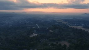 Orbit drone shot of Borobudur Temple with magical light of sunrise sky in misty morning. the land still dark with an orange sky. Ancient Buddhist Temple. Magelang, Indonesia - 4K Aerial view