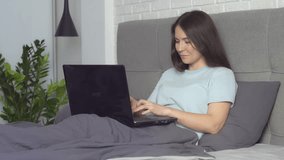 The girl communicates via video on a laptop in bed