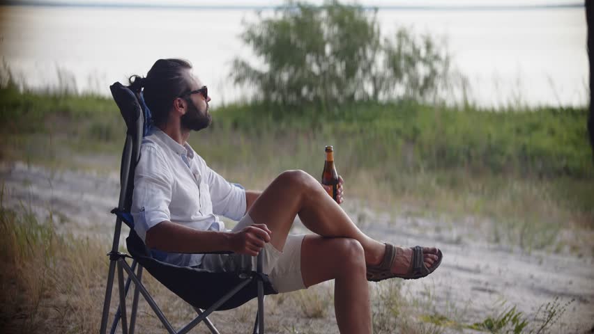 Weekend Chill Drinking Beer. Cool Refreshment At Serene Atmosphere. Pale Ale Beer Lover Chilled Beverages Tranquil Retreat. Sunset Sip Wheat Beer From Bottle. Calm Blissful Moment Sunset Reflection Royalty-Free Stock Footage #1108196705