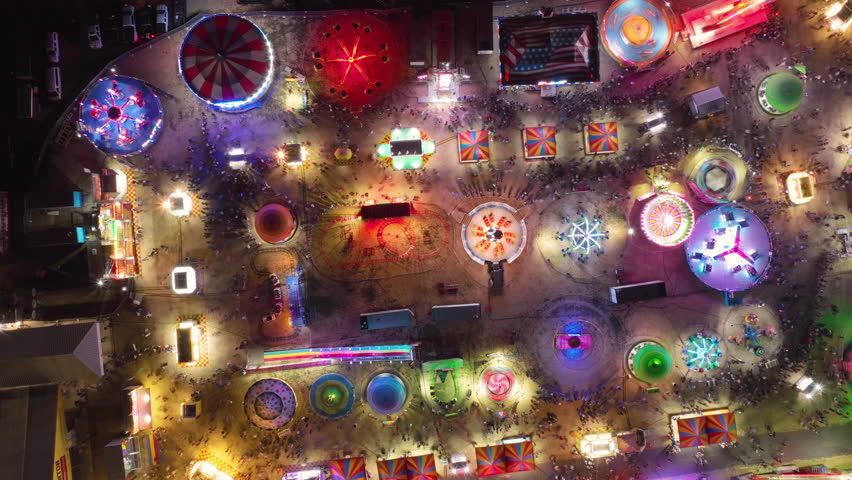 Aerial drone hyperlapse or timelapse of a colorful carnival festival at night with neon lights blinking as the cinematic drone films this top down view. Creative background concept with copy space. Royalty-Free Stock Footage #1108203273