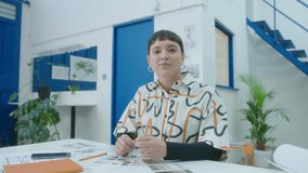 Young female architect sitting at desk in the office, looking at camera and explaining business project during online video call. Medium POV shot - Powered by Shutterstock - Get 15% off with code: PIKWIZARD15