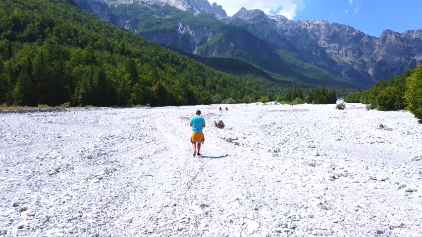 A young hiker walking along the dry river in summer through the Valbona valley, Theth national park, Albanian Alps, Albania