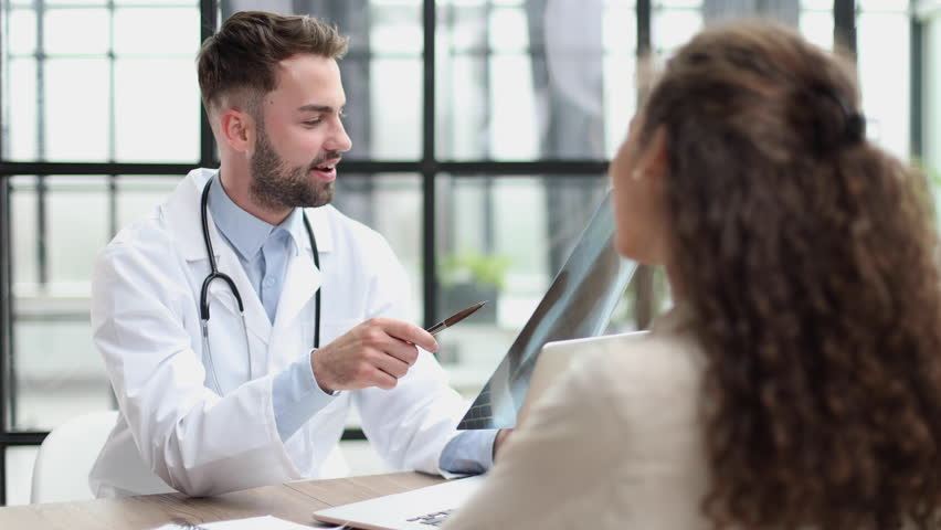 Young physiotherapist watching x-ray while sitting at the table at the reception - Powered by Shutterstock - Get 15% off with code: PIKWIZARD15
