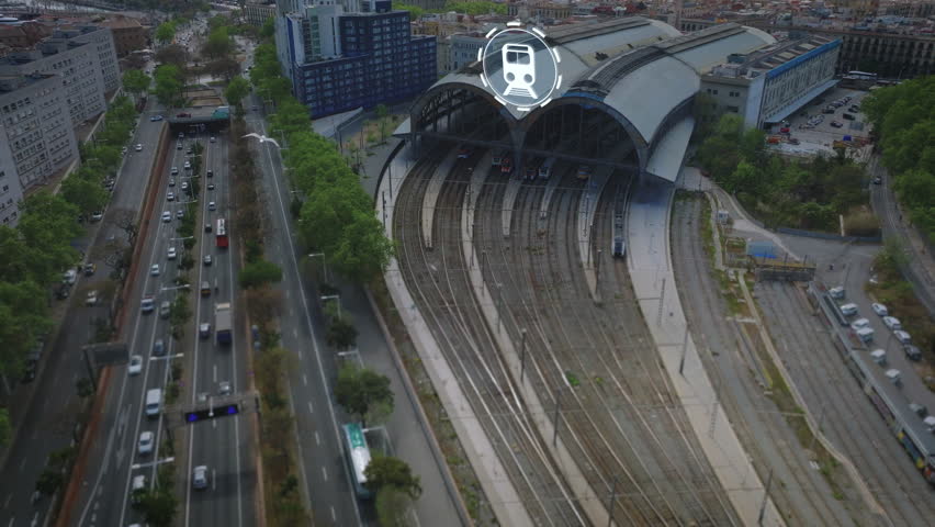 Aerial view of tracks and train station in city near busy multilane road. Computer added visual effects highlighting public transportation. Barcelona, Spain