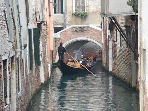 Venice: Gondola passage under a bridge along an unknown canal