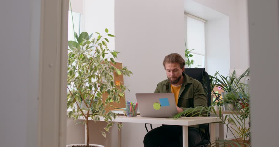 Serious man using laptop at home freelancer typing using keyboard at table workplace alone. Smart student using computer indoors, student learning information, studing online, man selling goods