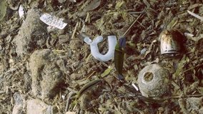 Vertical video, Close-up of seabed covered with a lot of plastic garbage. Bottles, bags and other plastic debris on the bottom in Mediterranean Sea, Plastic pollution of ocean bottom, Slow motion
