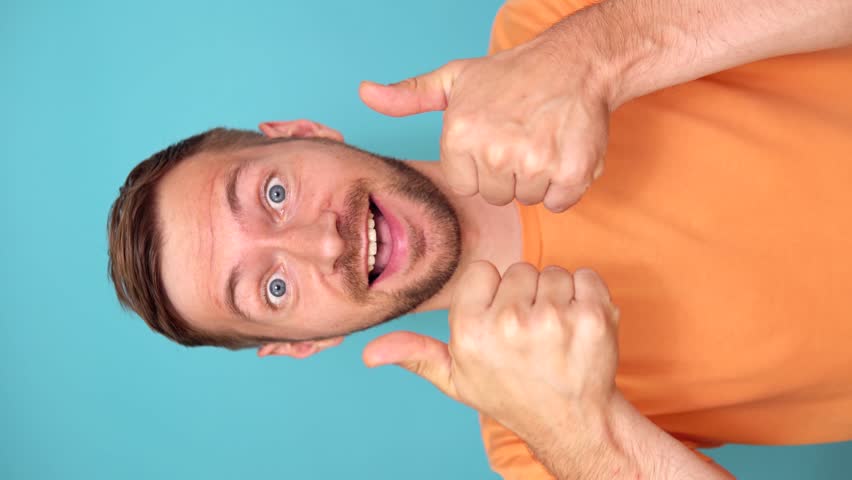 Young Man Cheering Success Over Blue Background, Gesture of Thumbs Up. Vertical video | Shutterstock HD Video #1108218745