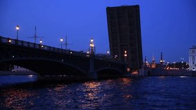 Side view from tour boat on open Trinity bascule bridge at night in Saint Petersburg city, Russia. Real time handheld video. Urban transportation building. Water travel business theme.