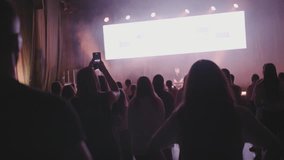 Hands of Female Christian Worshiping and Praising while Singing on Youth Festival Concert. People with Raised Arms on Music Live Event with Lights, recording video on smartphone mobile phone