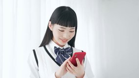 Asian schoolgirl in uniform using a smart phone.