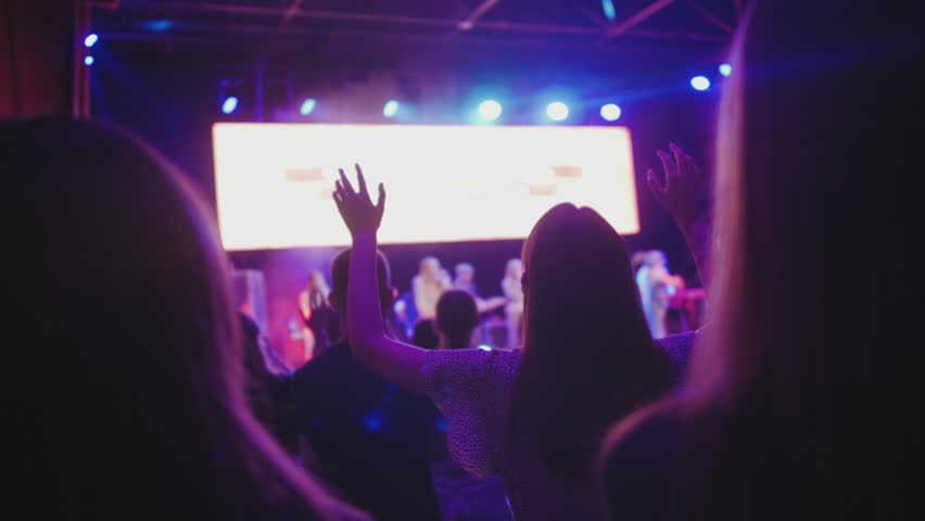 Christian conference, worship musical night, beautiful female raising lifting hands up, praising lord Jesus. Young people believers singing  Royalty-Free Stock Footage #1108237179