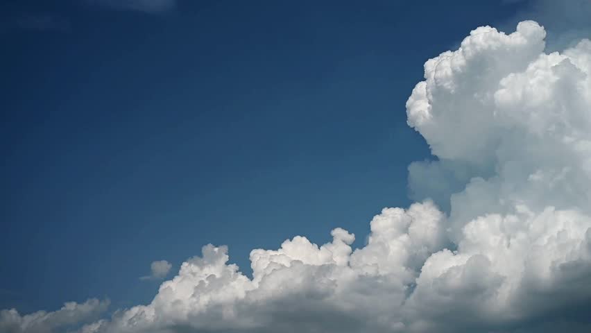 Timelapse of billowing white clouds in a blue sky. The clouds slowly build to fill most of the sky.
