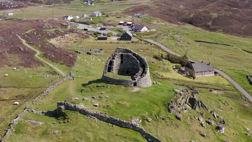 Drone shot circumnavigating the 'Dun Carloway Broch' on the west coast of the Isle of Lewis, part of the Outer Hebrides of Scotland. The broch is a tourist attraction first built around 100AD.