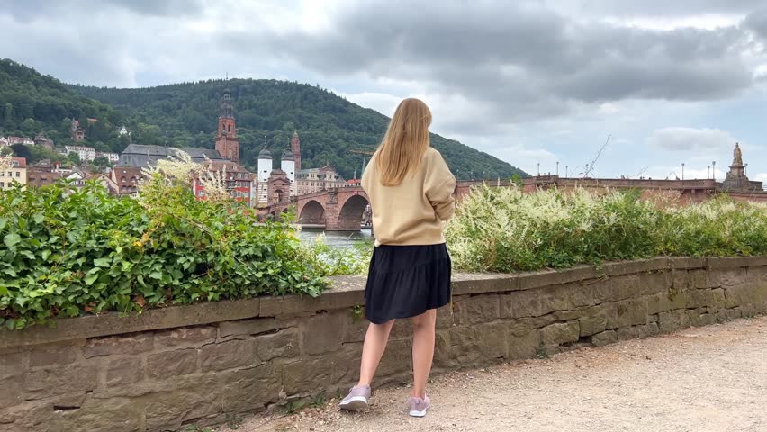 The girl takes pictures of herself on the phone against the background of the old city, communicates on the phone with friends, takes pictures of the city on a mobile phone, a tourist takes photos of 