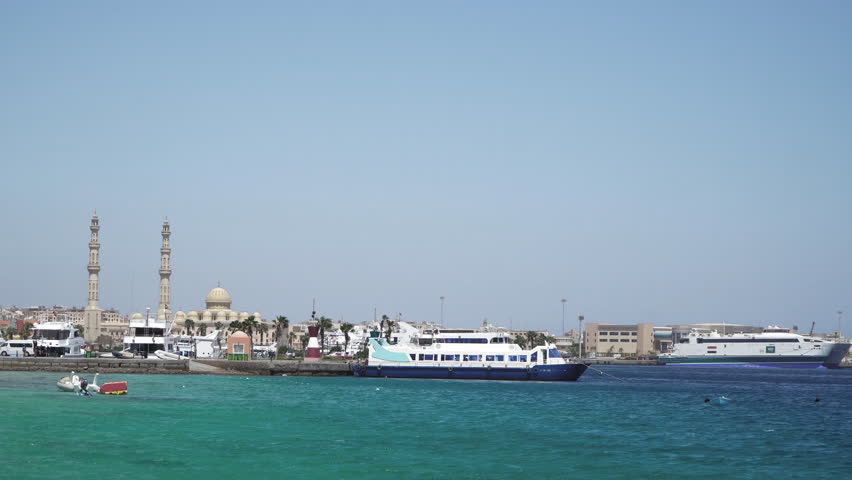 Seascape with motor yachts in marina. View of mosque in the background. Hurghada, Egypt