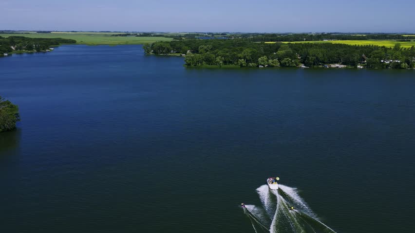 A Drone follows a Family speed boat pulling two wakeboarders on Killarney Lake in Turtle Mountain South West Manitoba Canada