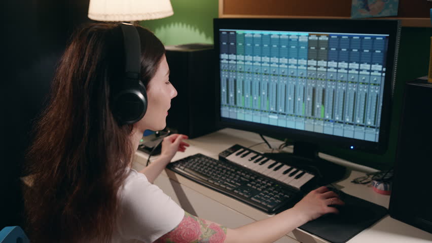 Music production studio. Asian Girl in headphones listening music, smile. Producer Woman working in the recording studio with computer and mixer creating music in sound recording studio. Professional