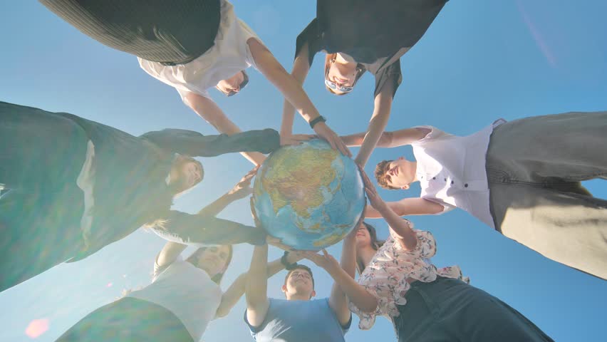 Friends holding a geographical globe in their hands. The concept of keeping the world safe.