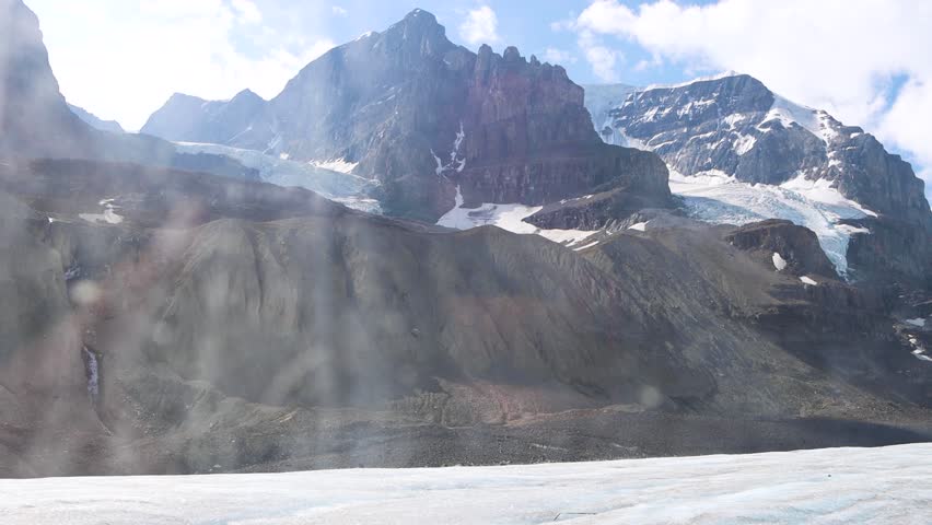 View of Athabasca Glacier from Ice Explorer, surrounded by tall snow capped mountains in the Rocky Mountains, Alberta, Canada. Blue glacier ice with deep crevasses. Jasper National Park.