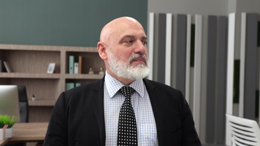 Pleased, happy middle-aged Caucasian bald man with grey beard in formal wear with black jacket standing in modern office, smiling. Well-furnished office. High quality 4k footage Royalty-Free Stock Footage #1108252827
