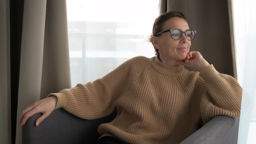 Happy woman in armchair enjoying the views from the window