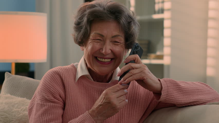 Happy laughing talking phone Caucasian old woman carefree senior lady listening funny news smile laugh retired grandma elderly female grandmother mobile conversation smartphone communication at home