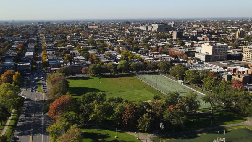 Aerial view of football field near houses in old Montreal district, Canada at autumn. View of Mont Royal mountain park.  Drone footage  on sunset.