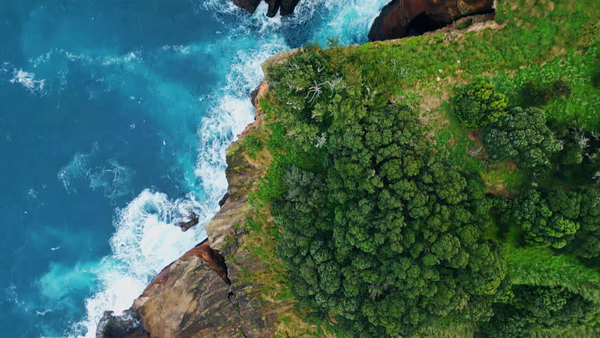 Foaming turquoise sea splashing at stoned cliffs. Aerial top view wild mountains covered by green mangrove woodland at summer day. Dangerous blue lagoon waves washing rocky peninsula hitting seashore