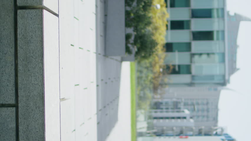 Business man typing laptop sitting urban bench moving camera vertical shot. Dark clothes freelancer working remotely answering email on street back view. Male person texting computer preparing project
