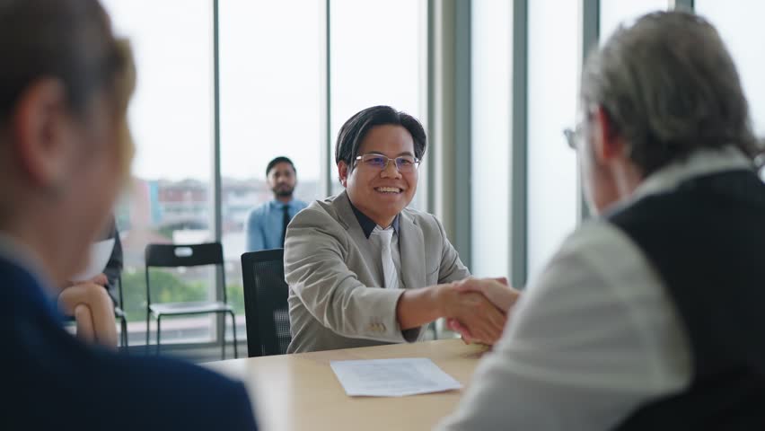 Asian candidate man shaking hands with human recruiters after sucessful job interview in conference room. Job interview and employment concept
