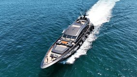 Aerial drone tracking video of beautiful modern super yacht with wooden deck cruising in high speed in Aegean deep blue sea