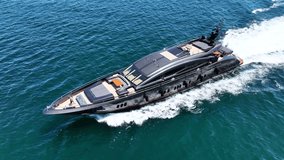 Aerial drone loop video of beautiful modern super yacht with wooden deck cruising in high speed in Aegean deep blue sea