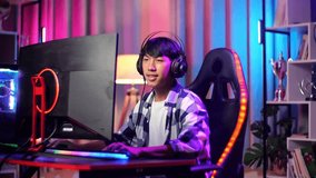 Asian Teen Boy Gamer Smiling To Camera While Playing Video Game On Computer
