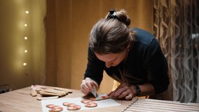 Warm Christmas home interior, a young woman is decorating gingerbread cookies in the shape of candy canes with icing. - Powered by Shutterstock - Get 15% off with code: PIKWIZARD15
