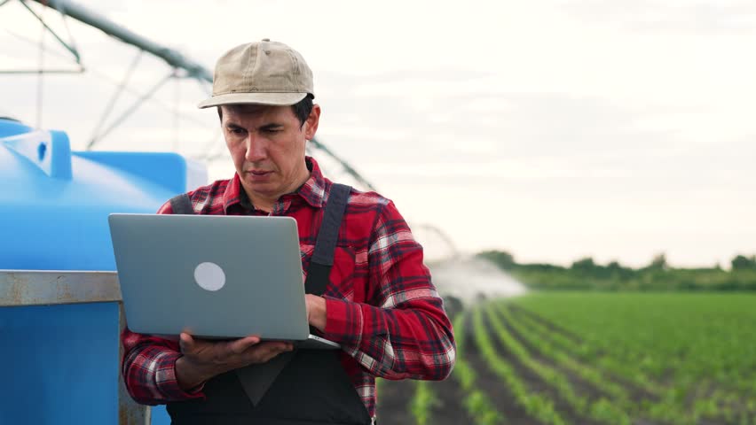 Agriculture.Farmer engineer is work with laptop in field.Automatic irrigation system for organic products on farm.Work engineer adjusts operation of irrigation system on farm.Agriculture food concept Royalty-Free Stock Footage #1108280669