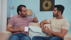 Serious indian father discussing with son while having coffee at home - concept of Parental Advice, family Mentorship and sharing Life Lessons - Powered by Shutterstock - Get 15% off with code: PIKWIZARD15