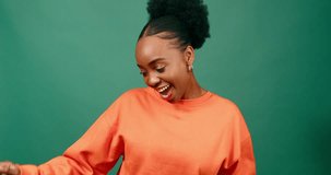Young Black woman dancing and smiling, green studio background