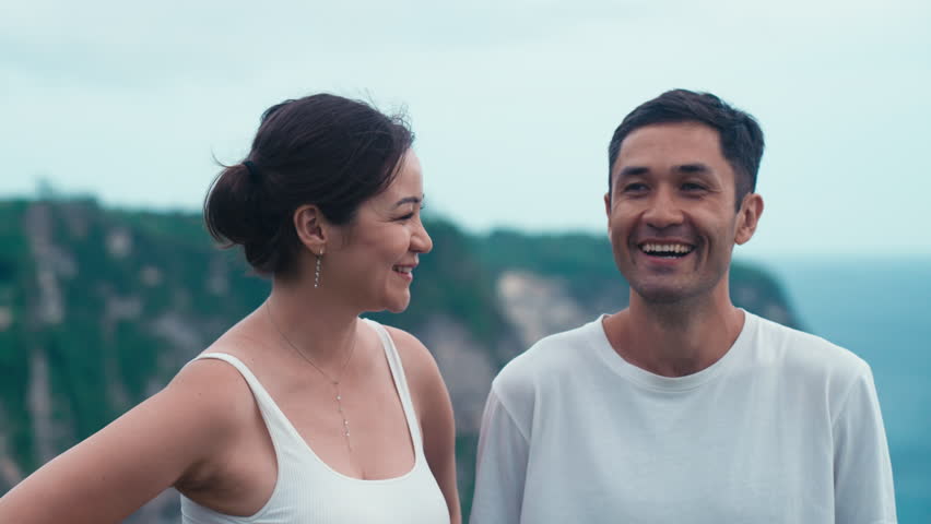Asian man and woman they look at each other and laugh and talk. Enthusiastic emotional happy Korean couple. Travel moments for happy family on a wild seaside on summer holiday. Vacation on island Royalty-Free Stock Footage #1108287009