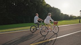 Back view of two married pensioners exercising with bicycles outdoors. Energetic senior couple cycling on asphalt road and enjoying nature view. Healthy activities concept. - Powered by Shutterstock - Get 15% off with code: PIKWIZARD15