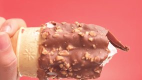Vertical video of hand taking chocolate ice cream cone on red background with copy space
