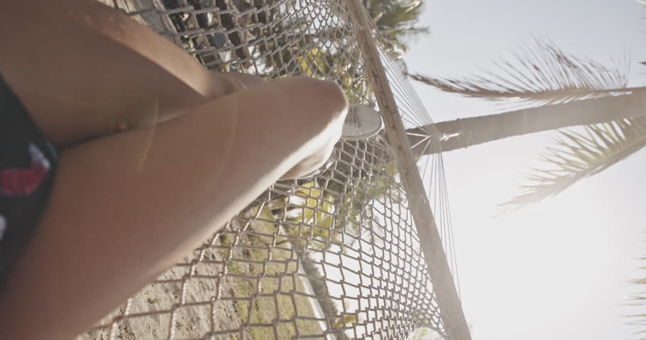 POV first person view Relaxed Woman legs in hammock on Fiji island. Relaxing in hammock, palm tree sunshine, enjoying the view of Pacific Ocean and white sand beach. Summer vacation, holidays, happy Royalty-Free Stock Footage #1108292583